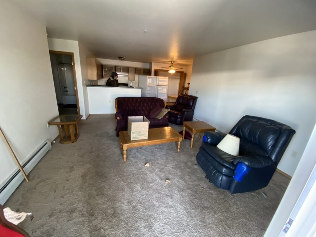 Living area with couches, chairs, tables, and a cardboard box.