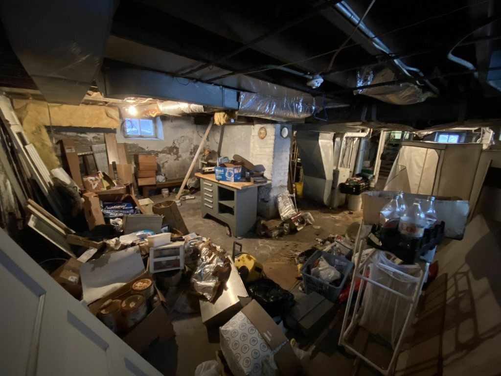 Packed basement containing boxes, furniture, and household items