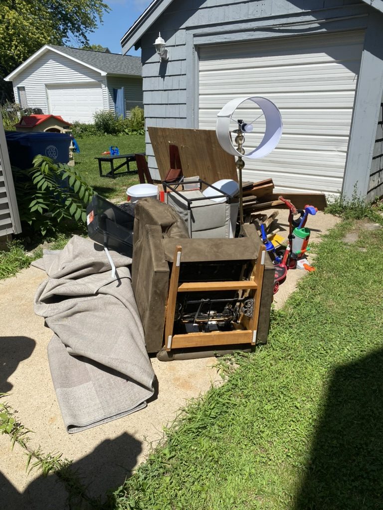 Pile of furniture and household items beside a garage