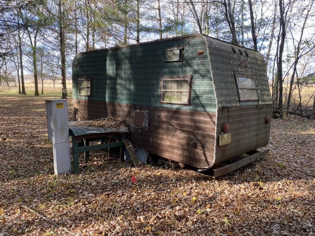 Older camper parked among trees.